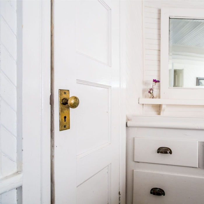 white bathroom with door and old hardware
